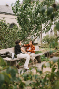 Twee vrouwen in gesprek op een bank in een park.