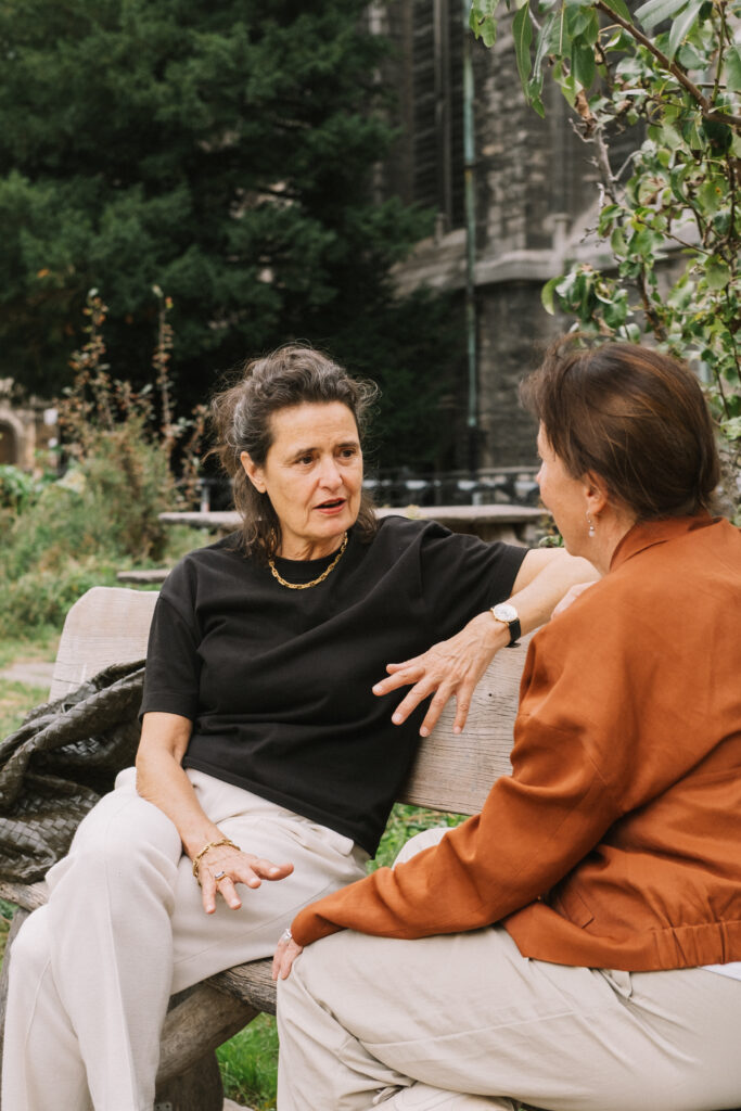 Twee vrouwen in gesprek op een bank in een park.