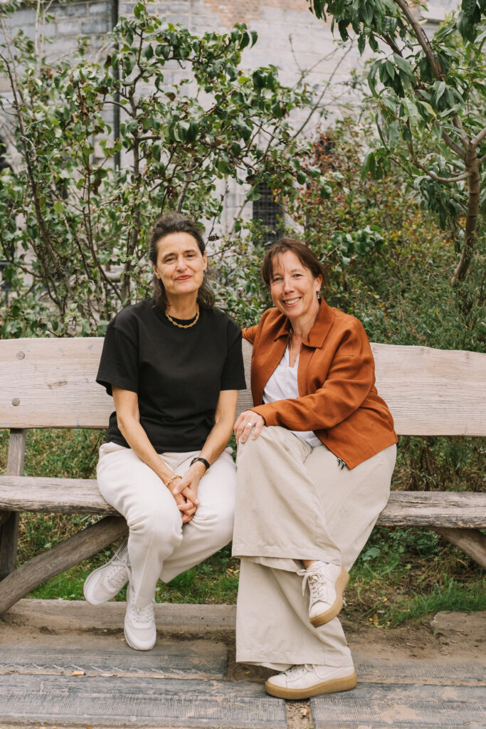 Twee vrouwen in gesprek op een bank in een park.